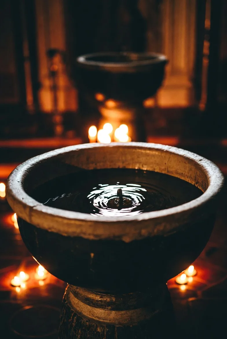 A bowl of water for baptism, with candles glowing around it
